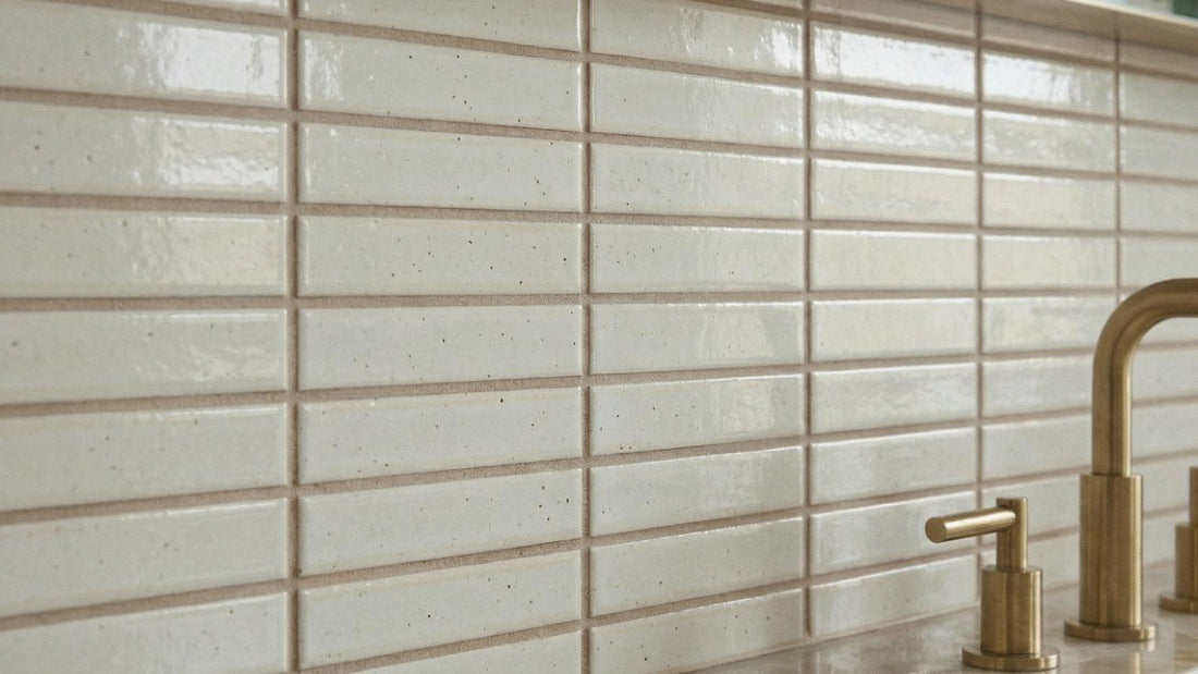 Glossy white kit-kat tile backsplash with a gold faucet.