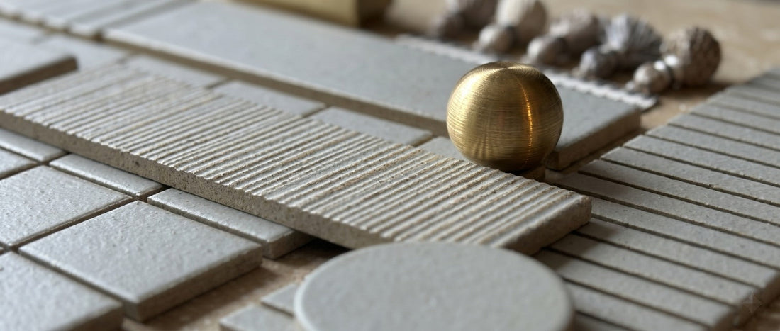 Textured stone tile samples with brass knob and drill bits background