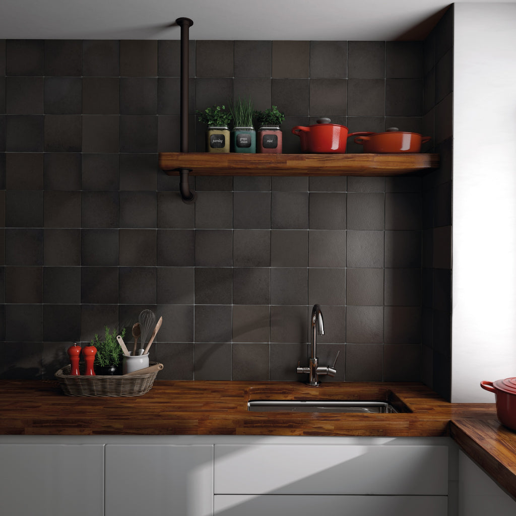Modern rustic kitchen featuring a matte charcoal tile accent wall, butcher block countertops, and an open wooden shelf.