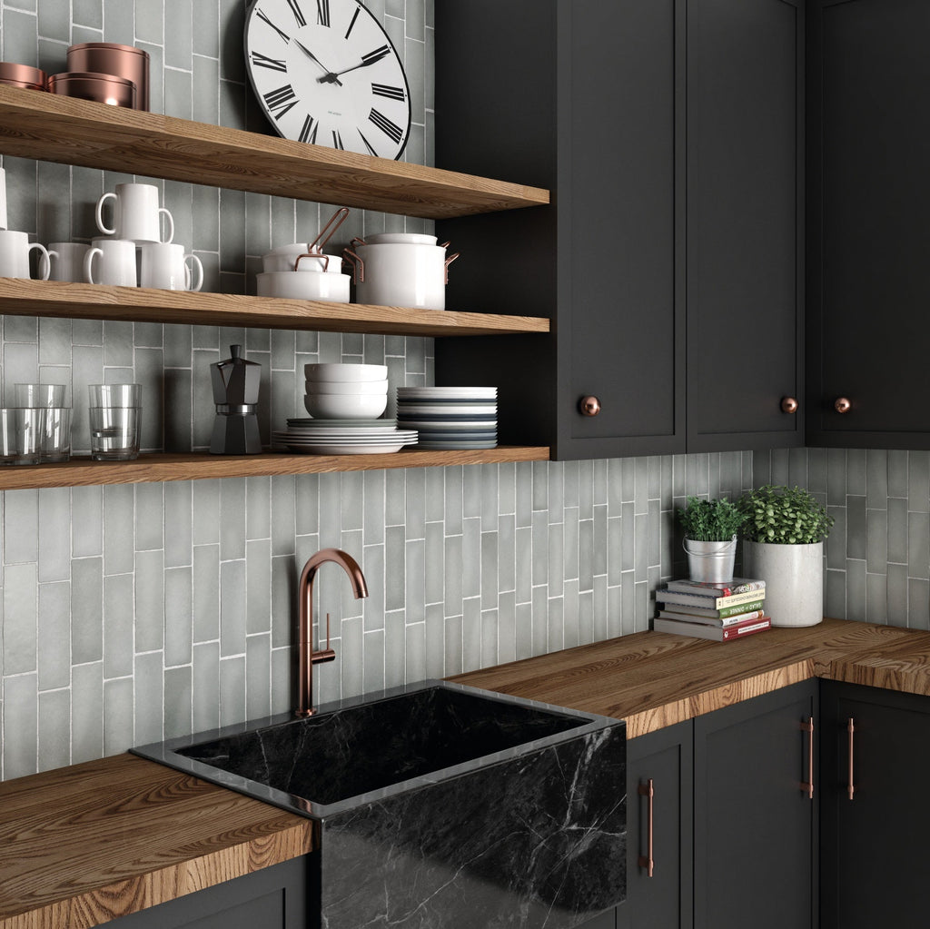 Modern kitchen featuring vertically stacked grey ceramic tiles, dark charcoal cabinets, and warm wood countertops.