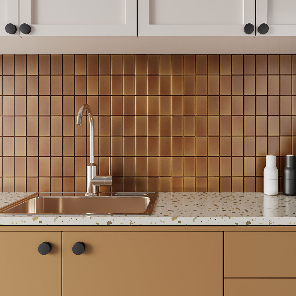 Modern kitchen featuring a metallic copper stack bond square tile backsplash, mustard yellow bottom cabinets, and terrazzo countertops.