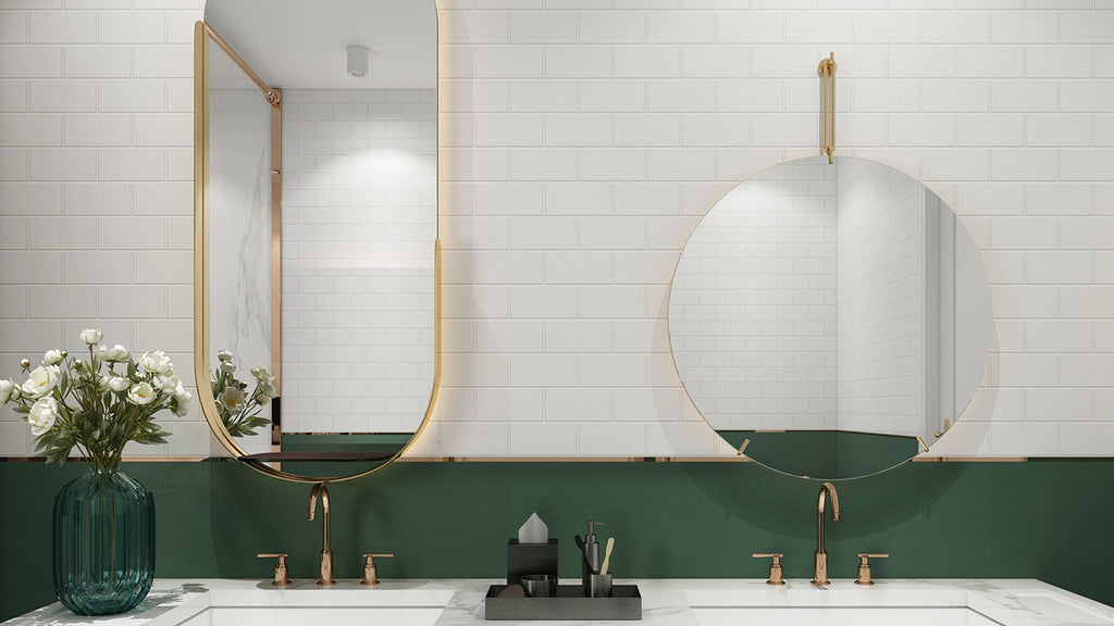 Elegant bathroom vanity displaying white subway tile walls, a dark green backsplash, gold fixtures, and custom mirrors.